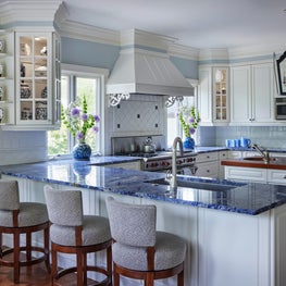 Kenilworth Kitchen. Blue quartzite countertops with raised panel cabinetry, blue walls, custom showcase cabinets & white tile backsplash.