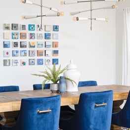 Contemporary linear chandelier, blue velvet chairs & rustic modern dining table.