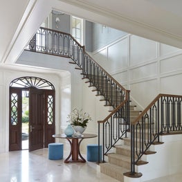 Mediterranean style entry with white backdrop, decorative banister and door trim.
