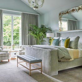 A serene master bedroom with cool tones and nice linens.