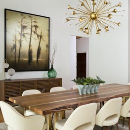 This contemporary dining room features Jonathan Adler’s “Sputnik” chandelier sparkles above Eero Saarinen chairs from DWR that line the dining room’s trestle table.
