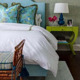 Grass cloth wallpaper and repainted green night table add a tropical vibe.