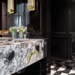 With lacquered-like black walls and a one-of-a-kind marble floating sink, this small space is filled to the brim with glam.