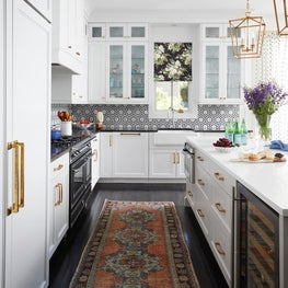 White kitchen with black flooring, gold and brass accents