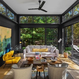 Modern living room with yellow accents, floor to ceiling windows, black walls