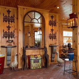 Entry hall to rustic family room with vintage mirror an wood paneled walls.