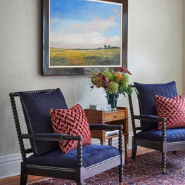 Historic Lake House Great Room. Black spindle chairs with navy herringbone upholstery, red geometric pillows & a Persian rug.