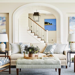Blue and white coastal living room with rattan chairs and custom upholstery