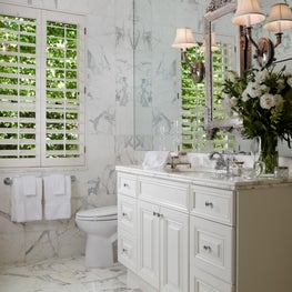 In the master bathroom, marble floors and walls highlight the white cabinetry. 