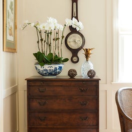 Creamy walls and  polished wood floors are accented by a vintage wood cabinet.