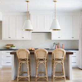 Bright white kitchen with backsplash tile by Heath Ceramics and woven stools.