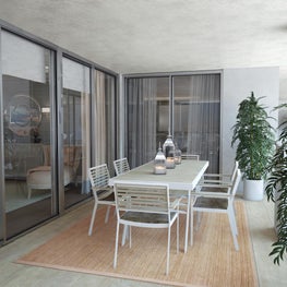 Outdoor dining in style with table and chairs resting on a sisal area rug.