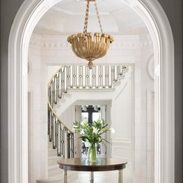 Soft tonal marble combinations and a sculptural railing in an entry hall