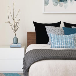 Modern guest bedroom with blue and white bedding, white nightstands, white walls