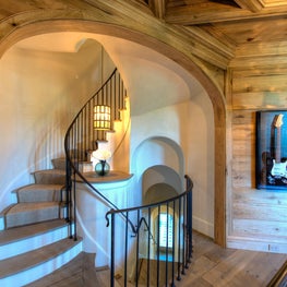 Curved Stair Beyond Wood Arch with Plaster Barrel Vaults and Iron Railing