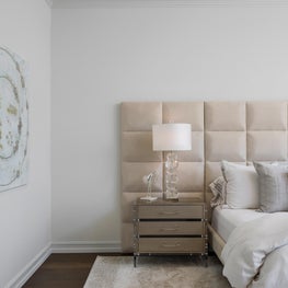 Expansive Decadent Waterfront, master bedroom, lucite furniture, neutral bedroom, upholstered headboard, lucite lamp, modern art