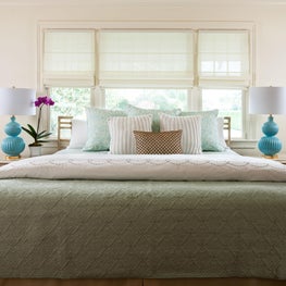 This vintage bed has turquoise mid century table lamps on either side.