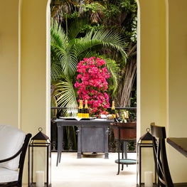 Flowers serve as organic decor next to the outdoor bar framed in an archway.