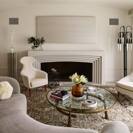 Living room with antique carpet and midcentury seating and floor lamp. 