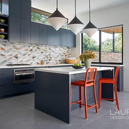 The pool house kitchen boasts dramatic lighting and dark orange accents.
