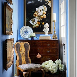 Cheerful hallway full of English antiques, chinoiserie, blue and white porcelains, and fabulous art! The periwinkle walls accented with warm gold tones pack in the charm in this historic home.