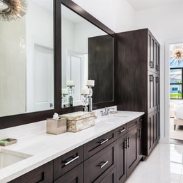 SLEEK CONTEMPORARY METALLIC RESIDENCE dark wood master bathroom, white countertops, full wall vanity mirror, modern chandelier