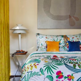 Tropical fabrics, vintage furniture, and modern art unite in this guest bedroom.