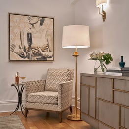 Art deco apartment with gold detailed armoir, printed chair, and modern art