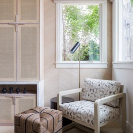Portfolio: A sitting area with upholstered chair with light wood legs and rattan ottoman in Pebble Beach, CA.