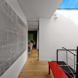 Clean modern hallway with skylight, red bench, large scale art