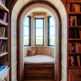 Arched Opening into Curved Bay Window Seat in Natural Wood Library