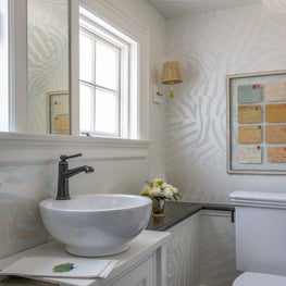 Wallpapered Bathroom with Ceramic Basin Sink and Letter Wall Art