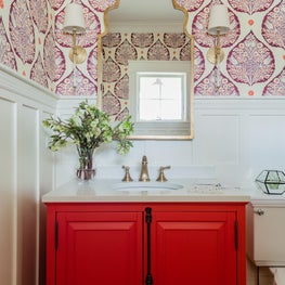 Colorful powder room bathroom with statement wallpaper white wainscot red vanity