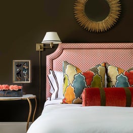 Chocolate walls, brass accents, and rich pops of color make guests feel at home