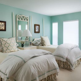 This serene bedroom has Tiffany blue walls and light ivory case-goods.