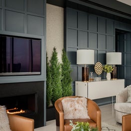Living room with leather club chairs and paneled wall designed by Robin Gannon Interiors