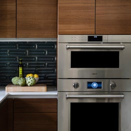 Portfolio: Dark wood cabinets and blue tile backdrop in a Poggenpohl kitchen