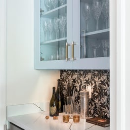 Custom bar with floral tile, bespoke cabinets, and wine fridge detail