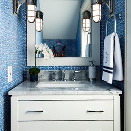 Crisp blue walls create a liveliness to this white powder room.