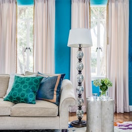 Colorful family room living room with patterned rug, glass floor lamp, teal wall