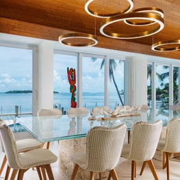 Cylindrical brass chandeliers spill rings of LED illumination over the table.
