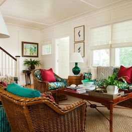 An eclectic living room with vintage wicker furniture and overstuffed cushions.