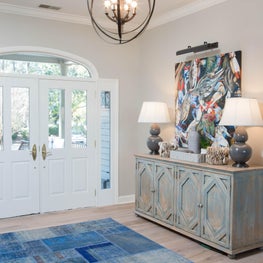 The entry sets the tone of this coastal South Carolina home with the ocean blue rug, vibrant Lowcountry artwork and oyster shell accessories!