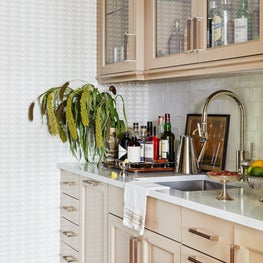 High-gloss painted cabinetry in bar with marble countertop and wallpaper