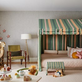 Colorful girls bedroom with striped tented bed and safari chair with built in bookcase