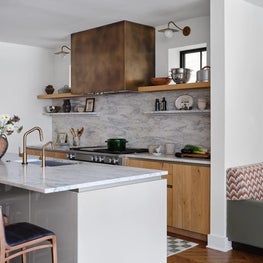 Kitchen with Stone Backsplash and Brass Hood