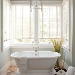 Windowed niche, stone floor and coastal accessories make for an inviting bath