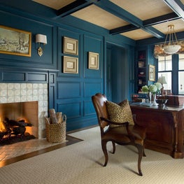 Library with blue-paneled walls, tile fireplace, coffered ceiling