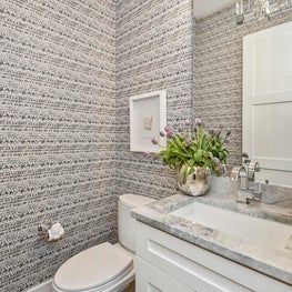 Geometric patterned wallpaper adds a whimsical flair to this powder room.
