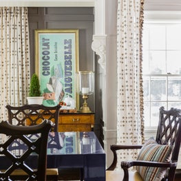 Dining room with navy black lacquer elements, gold hardware, vintage posters